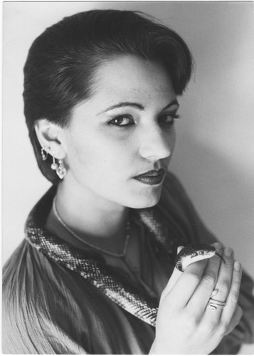 Black and white portrait of Karin Gurtner from 1979, wearing a snake around her neck and holding its head in her hand.